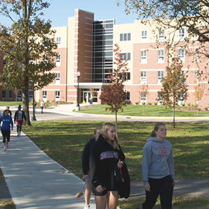 exterior shot of east hall with students walking on the sidewalk